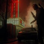 Alan Wake 2 - Alan Wake caminando armado frente al cine Coliseum bajo el letrero de neón rojo de Bright Falls
