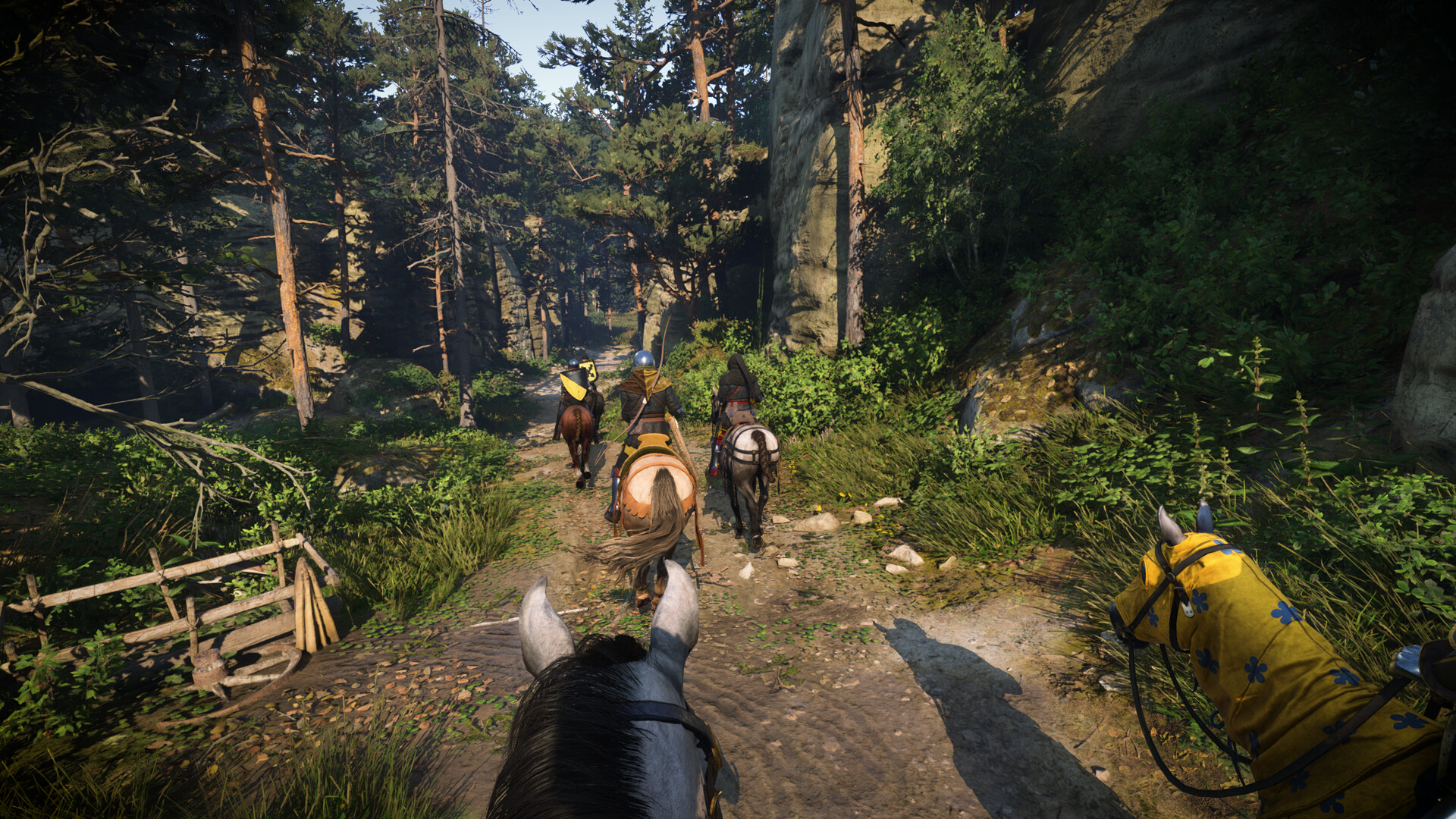 Kingdom Come Deliverance 2 - vista a caballo por un camino de bosque con otros jinetes delante - Juegosrpg.com