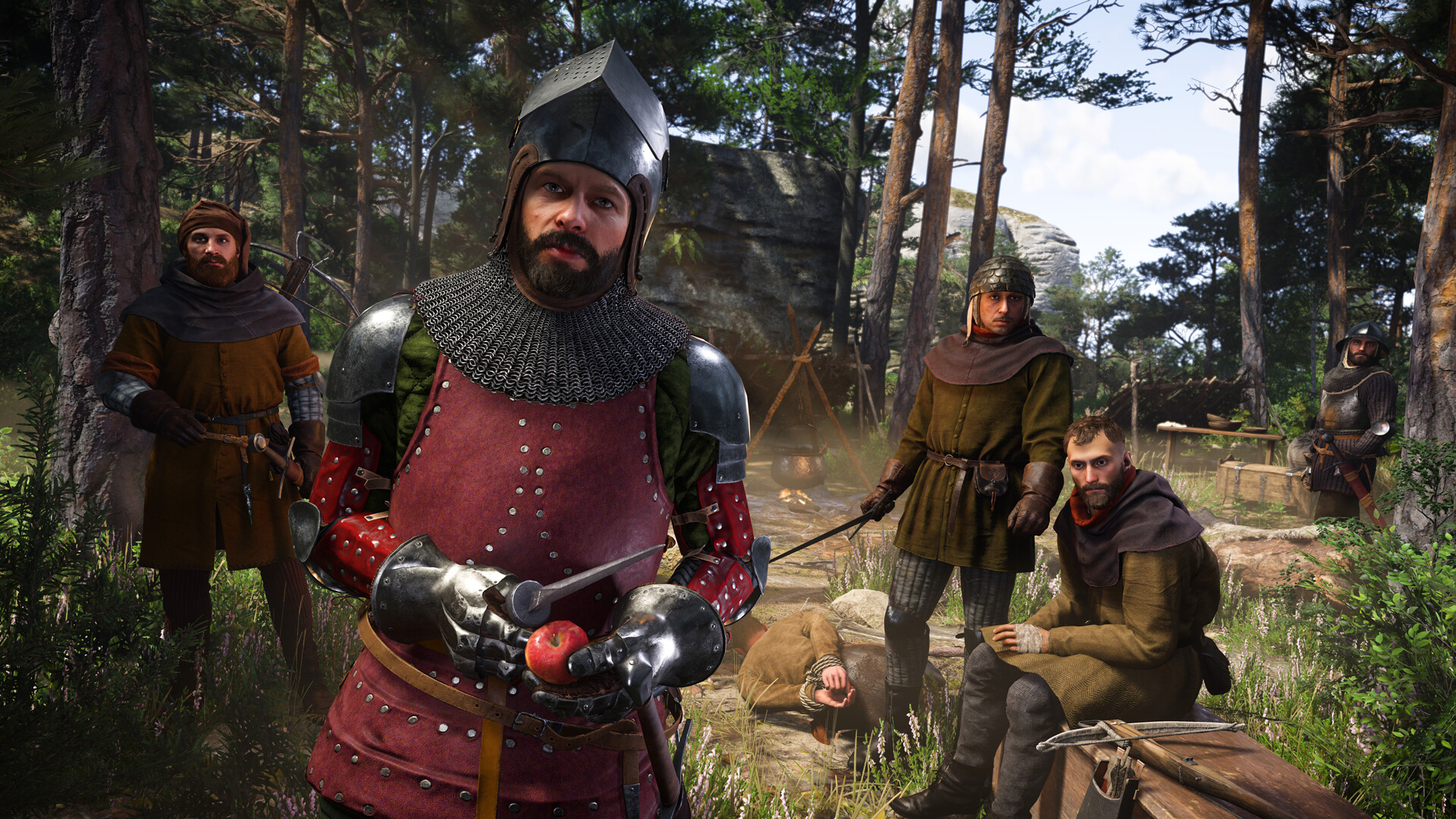 Kingdom Come Deliverance 2 - Henry con armadura de malla y gambesón junto a varios personajes en un claro del bosque - Juegosrpg.com
